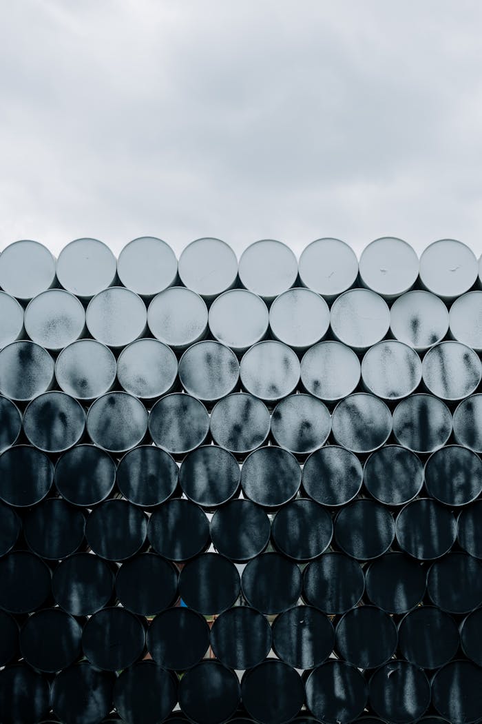 about-01 A vertical shot of stacked industrial barrels displaying a unique pattern and texture against a cloudy sky.
